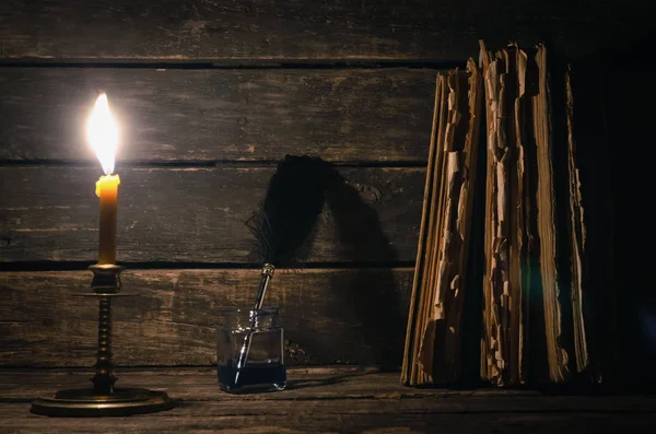 Quill'in kalem inkpot ve yazar Resepsiyon arka plan üzerinde yanan mum ışığında kitap yığını. Eğitim kavramı.