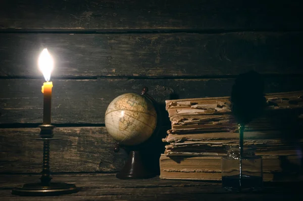 Quill'in kalem inkpot, küre ve yazar Resepsiyon arka plan üzerinde yanan mum ışığında kitap yığını. Eğitim genel kavram ya da seyahat günlüğü.