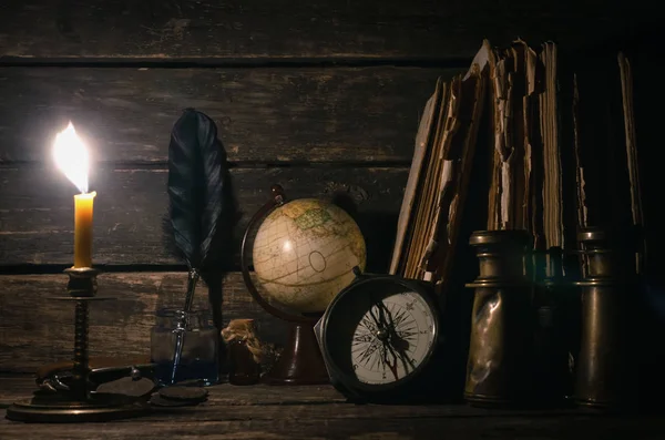 Travel or adventure concept background. Compass, binoculars, globe map, stack of books, quill pen on the adventurer table.