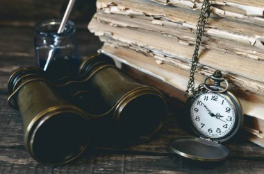 Seyahat ya da macera kavramı geçmiş. Cep saati, dürbün, küre ve kitap, tüy kalem maceraperest masada yığını.