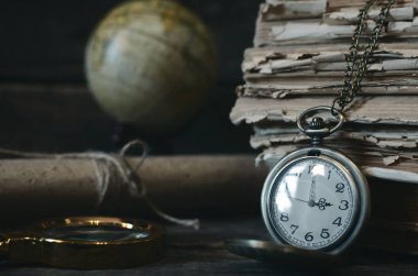 Seyahat ya da macera kavramı geçmiş. Cep saati, dürbün, küre ve Kitaplar ve Büyüteç Camı maceraperest masada yığını.