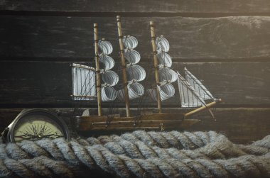 Yelkenli, deniz pusula ve ahşap bir kaptan masa arka plan üzerinde demirleme ipi. Deniz seyahat konsepti.