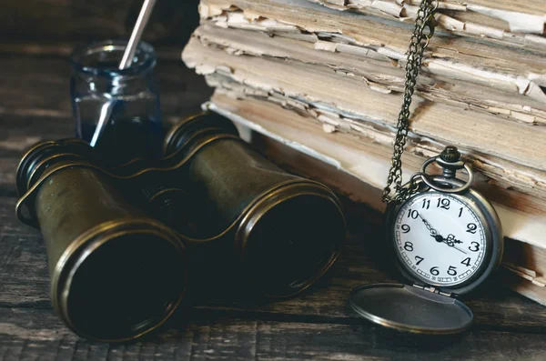 Seyahat ya da macera kavramı geçmiş. Cep saati, dürbün, küre ve kitap, tüy kalem maceraperest masada yığını.