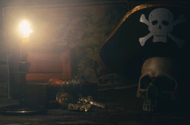 Yanan mum arka plan ışığında bir korsan Kaptan masada Kaptan şapkalı bir altın ve insan kafatası korsan harita ve hazine sandığı.