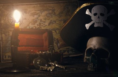 Yanan mum arka plan ışığında bir korsan Kaptan masada Kaptan şapkalı bir altın ve insan kafatası korsan harita ve hazine sandığı.