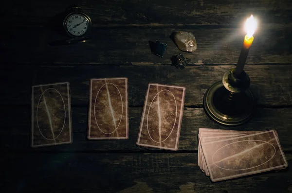 Tarot cards on fortune teller table in the lights of burning candle background. Futune reading concept. Divination.