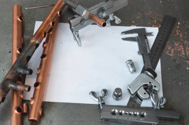 Pirinç borular, boru rammer, boru kesici Aracı, Çap pergeli, pense ve boş düzen taslaklar üzerinde tesisatçısı bir tezgah.