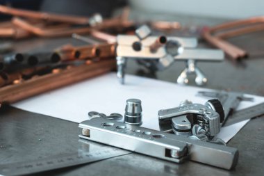 Pirinç borular, boru rammer, boru kesici Aracı, Çap pergeli, pense ve boş düzen taslaklar üzerinde tesisatçısı bir tezgah.