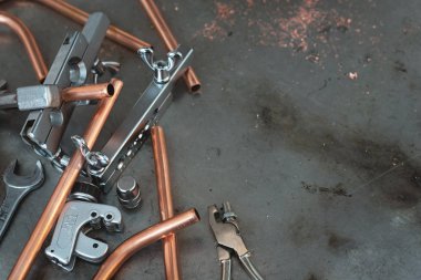 Rammer, kesici, pense, İngiliz anahtarı ve Pirinç borular tesisatçısı bir tezgah üzerinde boru. Boru işi kavramı arka plan kopya alanı ile.
