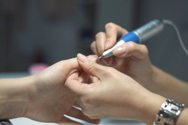 Manikürcü donanım manikür çivi salonda gerçekleştiriyor. Tırnak bakım kavramı.