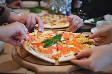 İnsanlar ellerini tarafından taze pizza Restoran masada paylaşıyorsunuz.