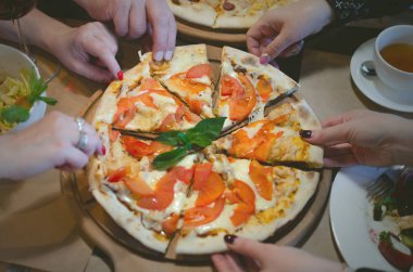 İnsanlar ellerini tarafından taze pizza Restoran masada paylaşıyorsunuz.