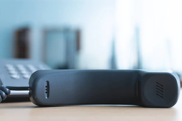 Phone handset laying on the office table. Phone line busy.