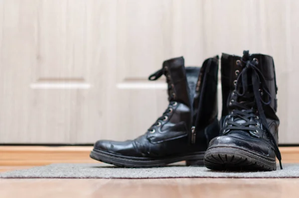 走廊地板上的黑色皮靴 — 图库照片