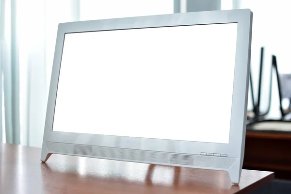 Blank screen computer monitor on a school desk in a classroom background.