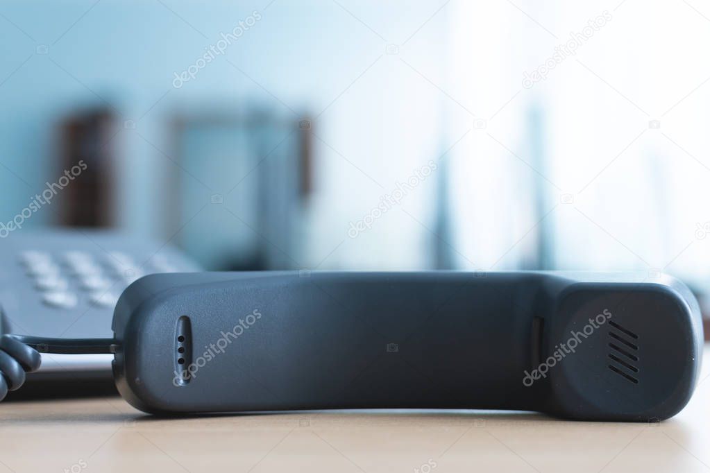 Phone handset laying on the office table. Phone line busy.