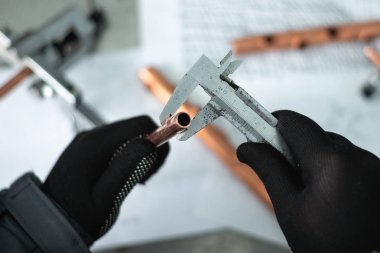 Mühendis bir pirinç boru elinde tutan ve bir çap Çap pergeli tarafından ölçme. Boru işi.