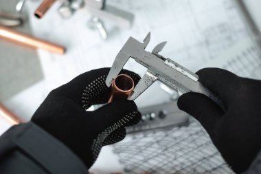 Mühendis bir pirinç boru elinde tutan ve bir çap Çap pergeli tarafından ölçme. Boru işi.