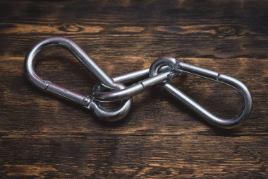 Kahverengi ahşap tahta arka plan üzerinde gümüş karabinalar.