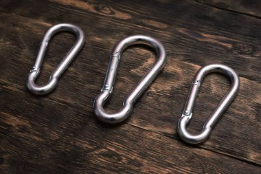 Kahverengi ahşap tahta arka plan üzerinde gümüş karabinalar.