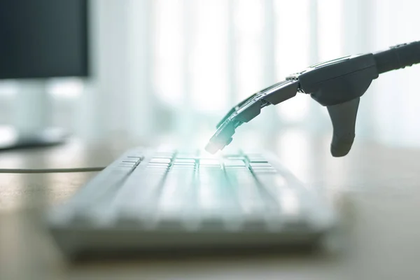 Robot with artificial intelligence is working on a computer. Robotic arm is pushing a keys on a computer keyboard.