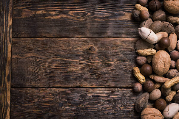 Пограничная рамка с копировальным пространством различных видов орехов на фоне коричневой деревянной доски
.