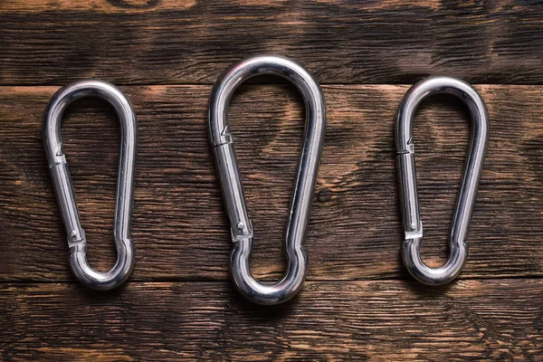 Silver Carabiners Brown Wooden Board Background — Stock Photo, Image