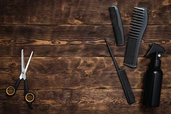 Hairdresser work table background with copy space. A various hairdressing tools such a hairbrushes, sprayer and a scissors on a wooden board.