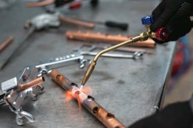 Alt tarafından bir darbe lamba fabrika tezgah arka plan üzerinde bir boru lehimleme. Boru işi.