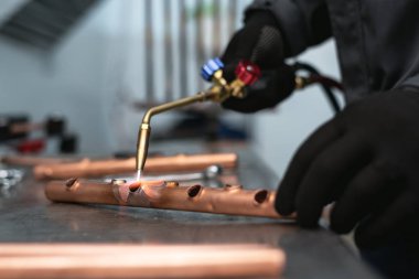 Alt tarafından bir darbe lamba fabrika tezgah arka plan üzerinde bir boru lehimleme. Boru işi.