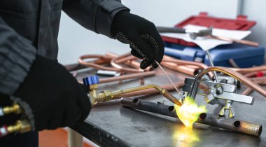 Alt tarafından bir darbe lamba fabrika tezgah arka plan üzerinde bir boru lehimleme. Boru işi.