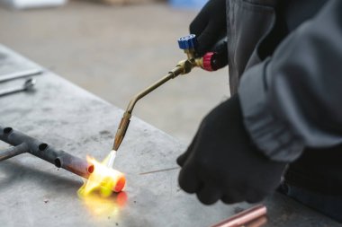 Alt tarafından bir darbe lamba fabrika tezgah arka plan üzerinde bir boru lehimleme. Boru işi.