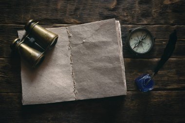 Boş Gezgin defter, dürbün ve deniz bir ahşap masa arka plan mockup pusulasına. Maceracı notlar. 