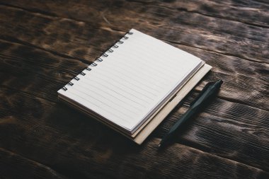 Kahverengi ahşap masa arka plan üzerinde boş kağıt yaprakları ile boş not defteri.