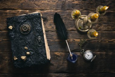 Antik sihirli kitap, cep saati, InkWell ve bir ahşap masa arka plan üzerinde yanan mum ışığında bir tüy kalem. Büyü kitabı.
