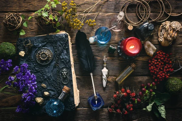 Spell book, magic potions and other various witchcraft accessories on the wizard table background.