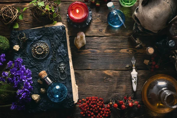 Spell book, magic potions and other various witchcraft accessories on the wizard table background with copy space.