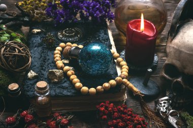 Spell book, magic potions and other various witchcraft accessories on the wizard table background.