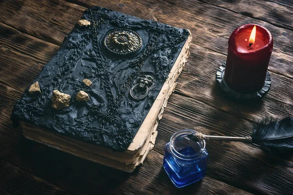 Ancient magic book, ink well and a quill pen on a wooden table background. Spell book.