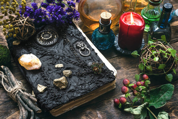 Spell book, magic potions and other various witchcraft accessories on the wizard table background.