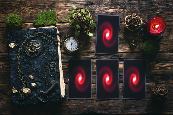 Tarot cards, book of magic and pocket watch on a wooden table background. Future reading.