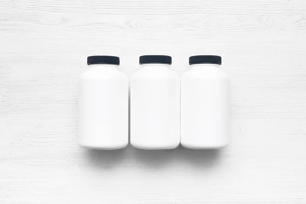 白色木制桌子背景上的运动营养罐 — 图库照片