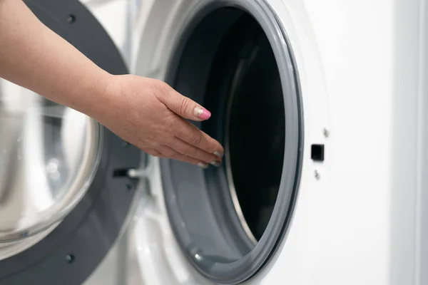 A young woman is choosing a new washing machine for home. Buying a new wash appliance.