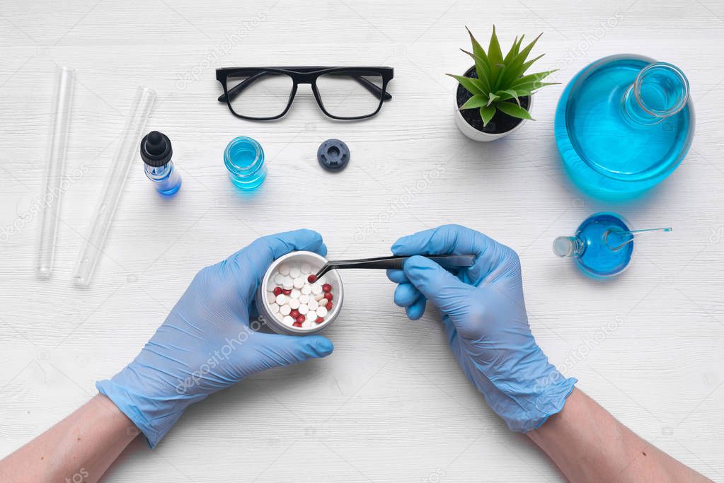 Man a scientist is performing a scientific experiment with a various reagent on a white table background. Pharmacology, pharmacy, medicine background.