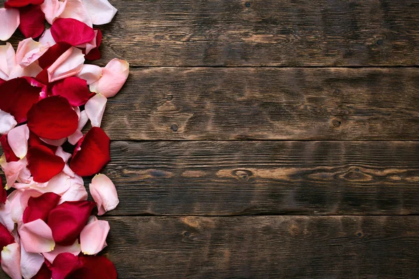 A pile of fallen rose flowers petals on a wooden floor background with copy space.