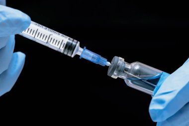 Şırınga ve bir şişe mavi ile sıvı bir doktor tıbbi bir eldiven eller. Tıp arka plan.