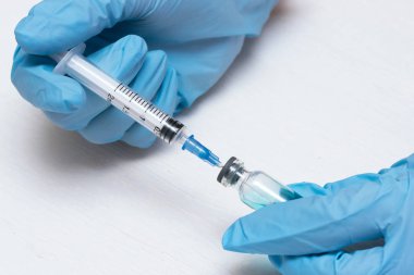 Şırınga ve bir şişe mavi ile sıvı bir doktor tıbbi bir eldiven eller. Tıp arka plan.