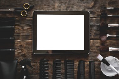 Makyaj sanatçı stilist tablo boş ekran dijital tablet bilgisayar, çeşitli saç fırçaları, kavanozlar ve şişeler ve makyaj fırçaları.