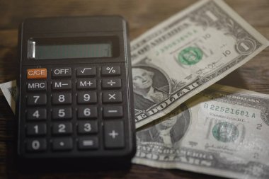 Hesap makinesi ve bir tablo üzerinde bir kaç dolar... Sıkı para. Para eksikliği. Mali sorunlar. İflas etmiş. Borçları kavramı ödeme.