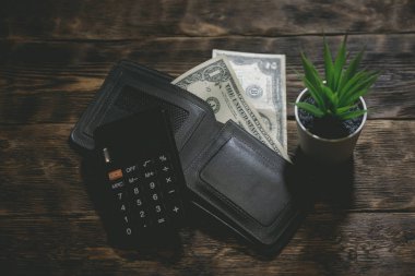 Hesap makinesi, m-cüzdan ve bir tablo üzerinde bir kaç dolar. Sıkı para. Para eksikliği. Mali sorunlar. İflas etmiş. Borçları kavramı ödeme.
